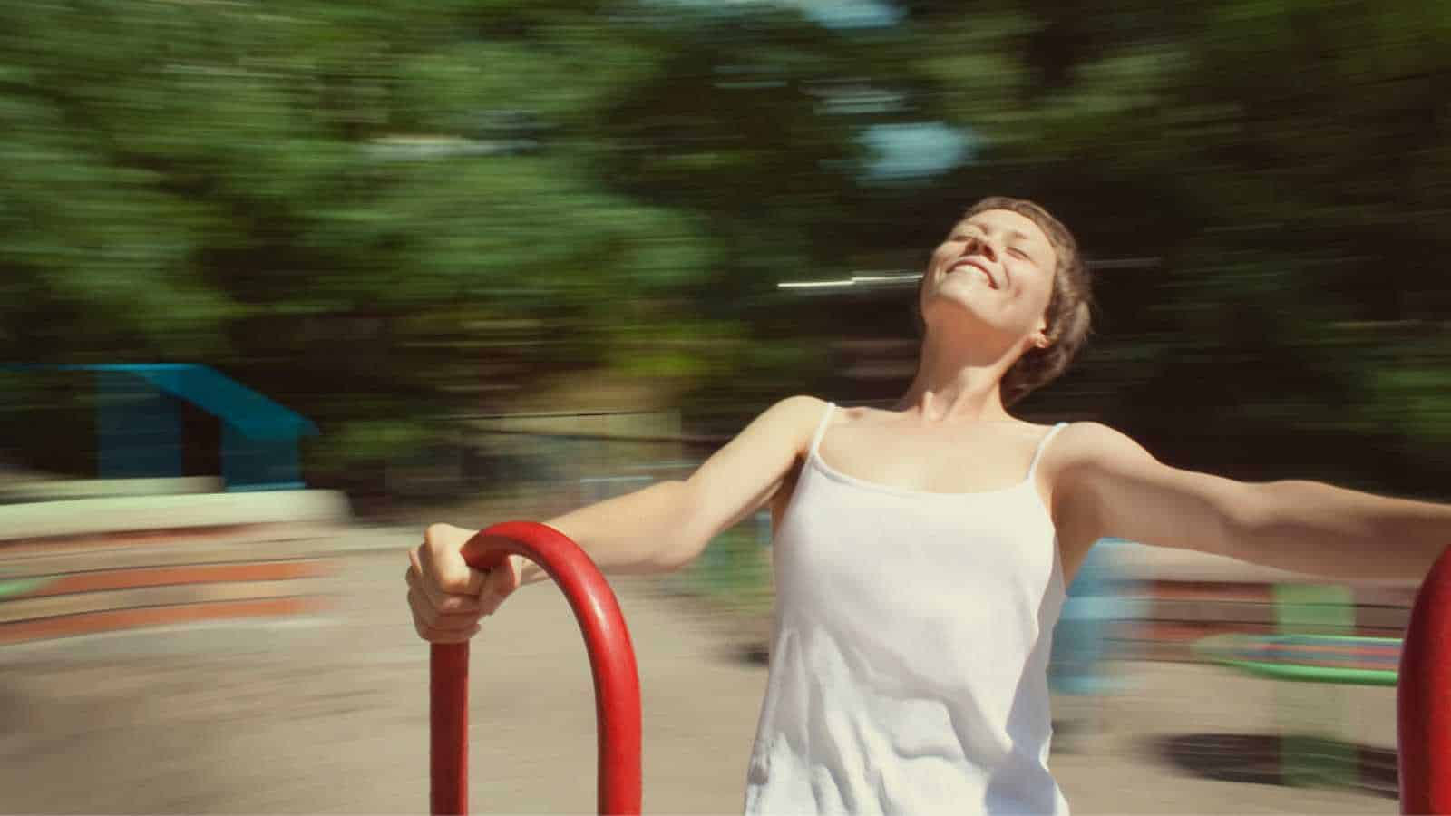 Girl spinning on the carousel, very happy. Head is spinning and the world around is blurred. Happy life, smiling girl and blurred background on the photo.