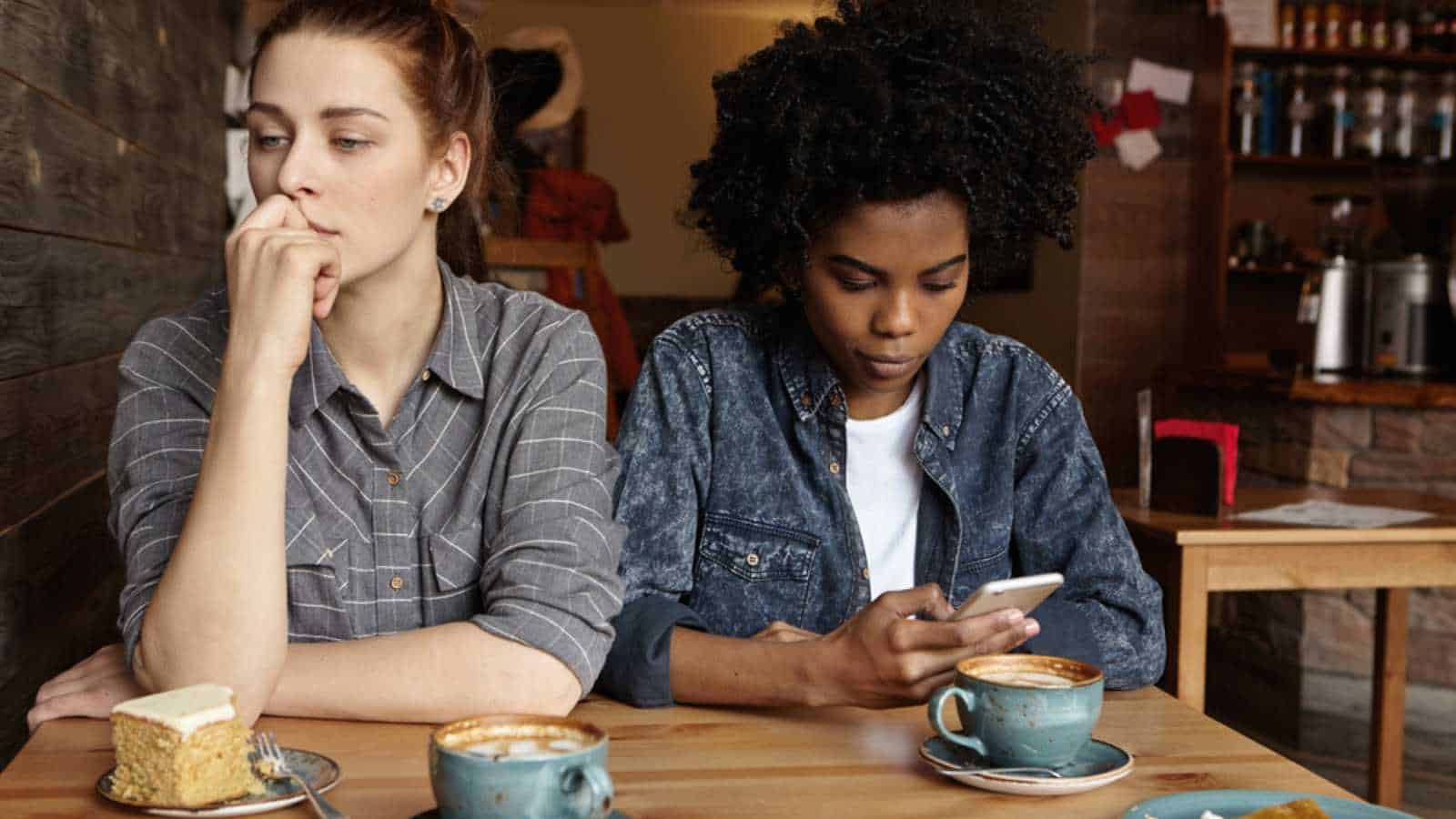 Woman scrolling mobile avoiding friend