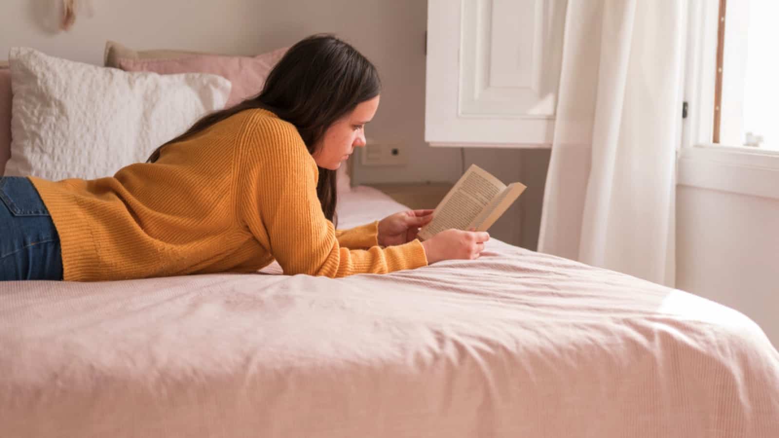 Adolescente lendo romance na cama