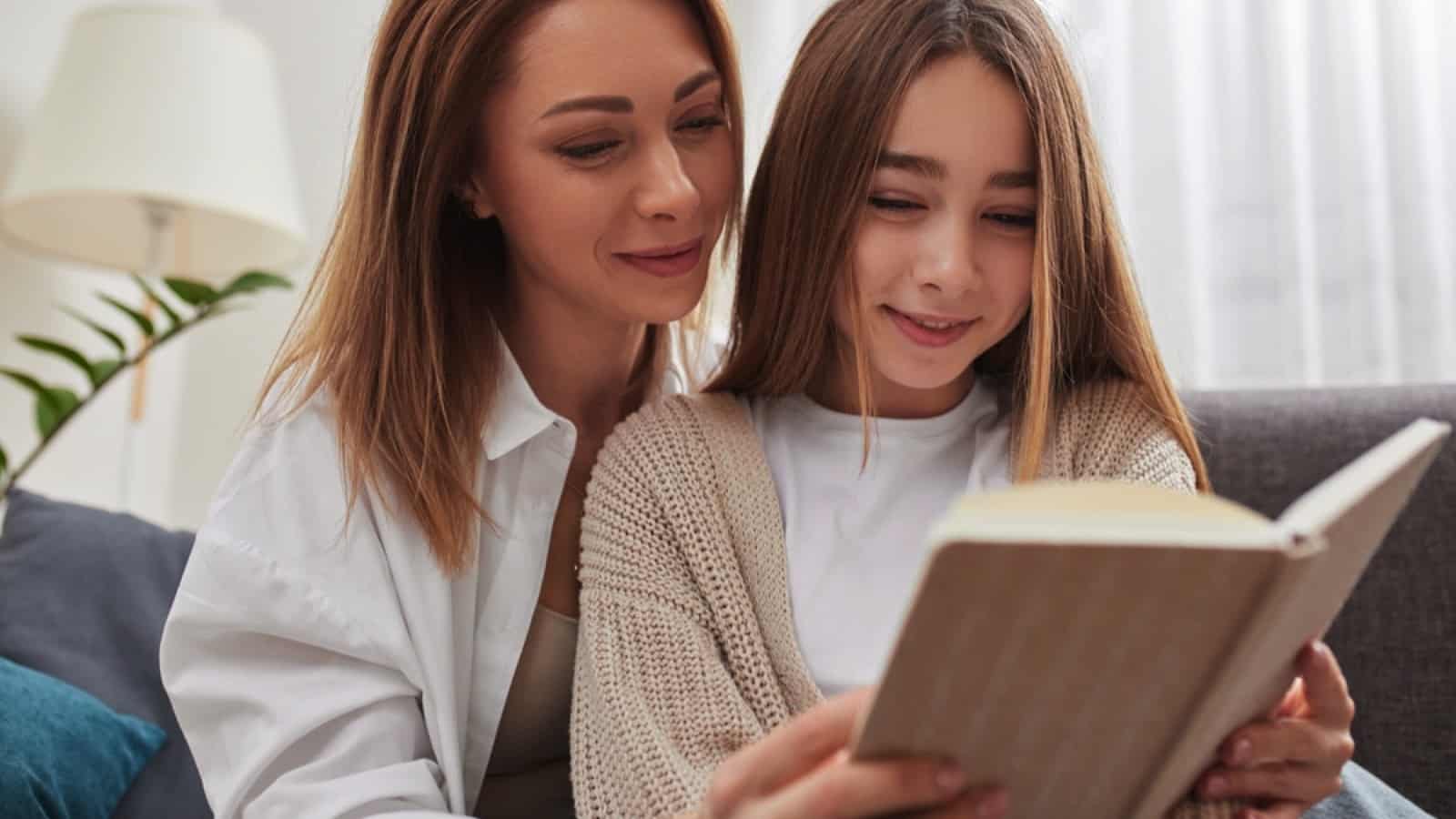 Girl reading book with mother