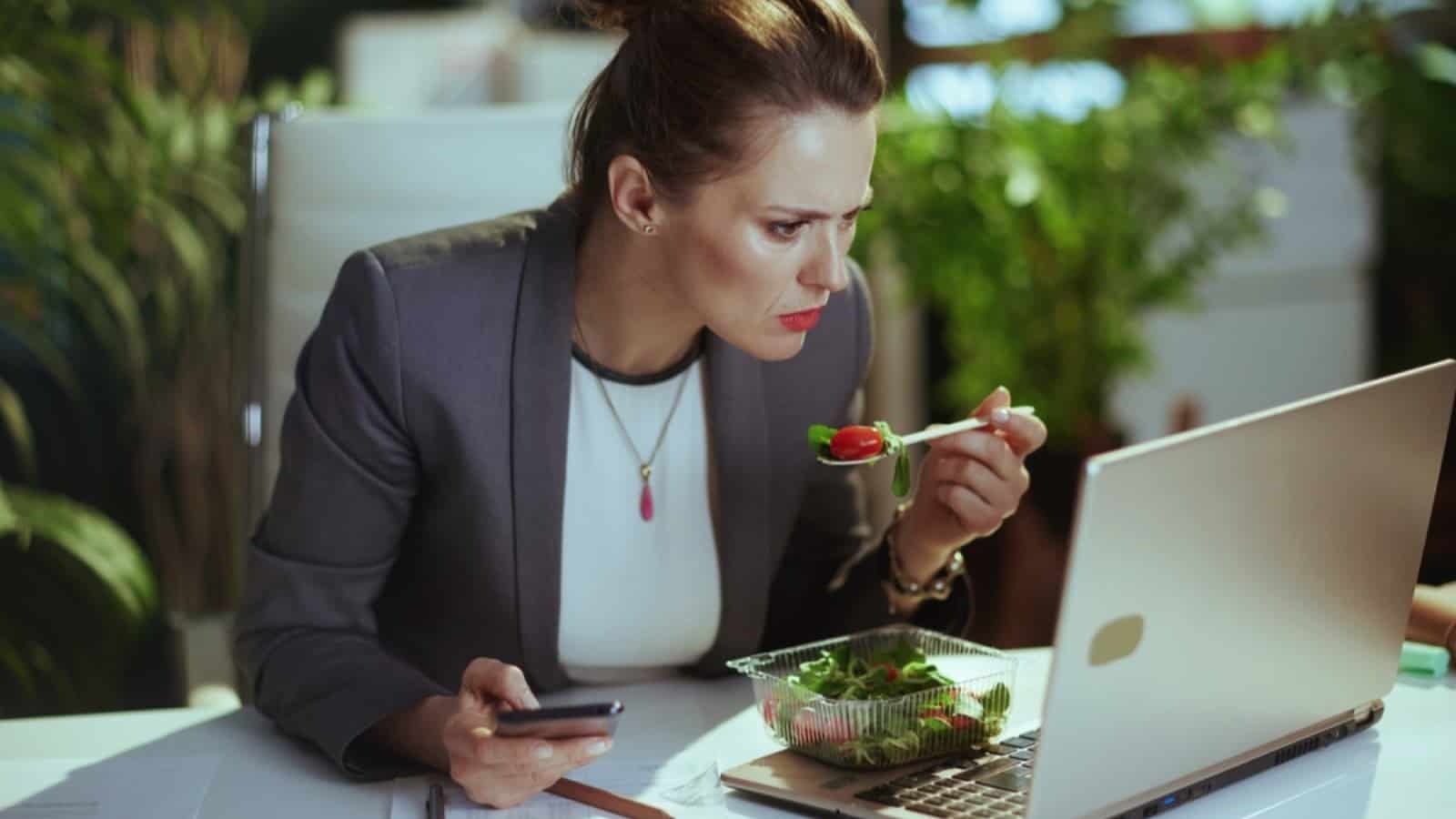 Middle aged woman eating salad in her workplace